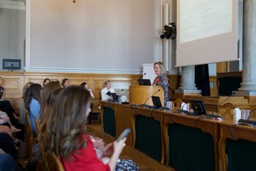 A speaker addressing the room, seen from the audience